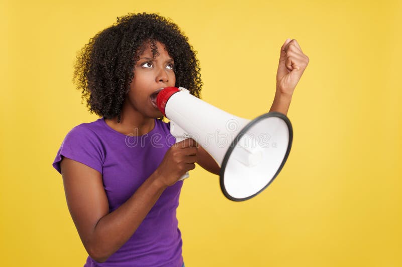 African woman yelling while using a mefaphone in studio with yellow background