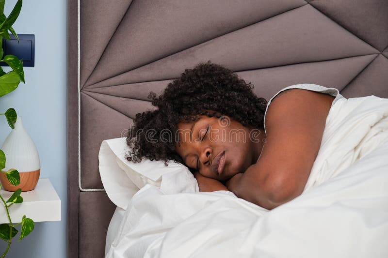 African Young Woman Sleeping on White Sheets in Bed. Stock Image