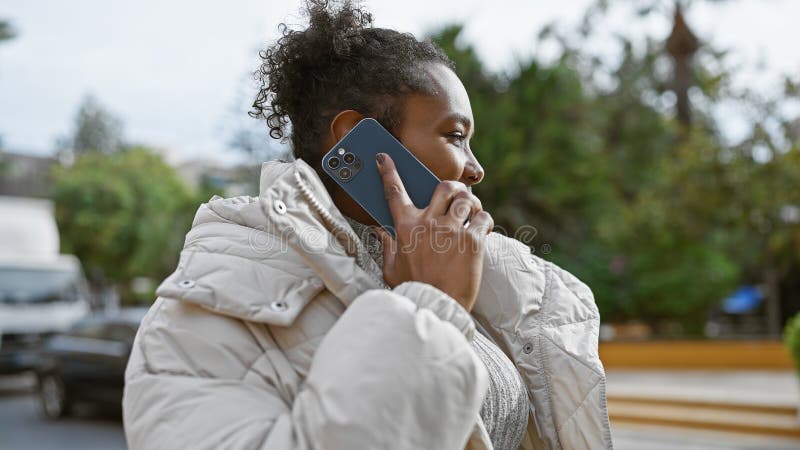 Africanamerican-kvinna i stadshus som pratar på smartphone-västar utomhus arkivbild