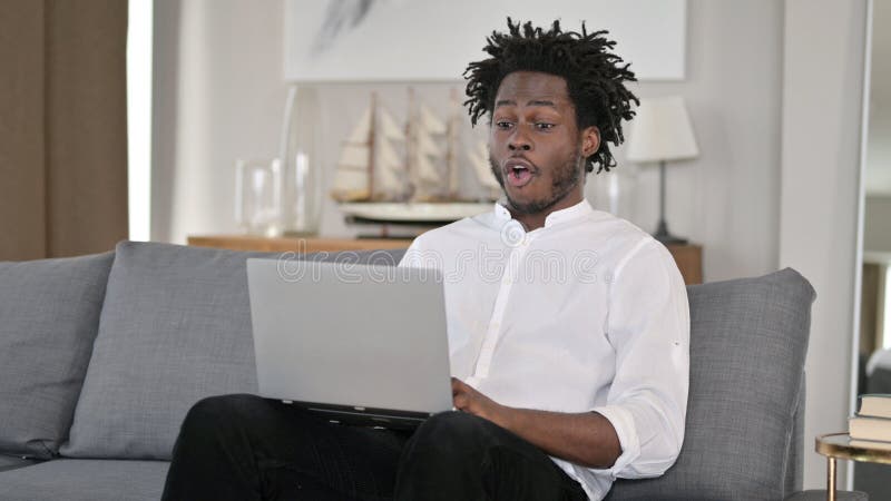 Africano com laptop chocado em casa imagens de stock