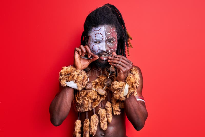 Africano nativo hombre en desgaste étnico utiliza cubiertos incorrectamente fotografía de archivo libre de regalías