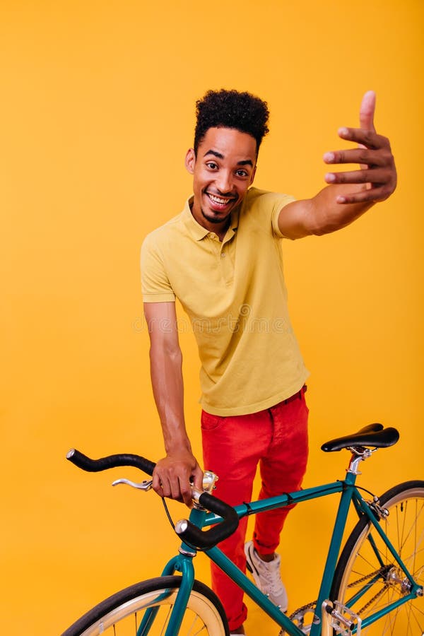 Africano, un uomo allegro che si pone con una bicicletta verde. Standi, immagine interna del modello maschile di brunette fotografia stock libera da diritti
