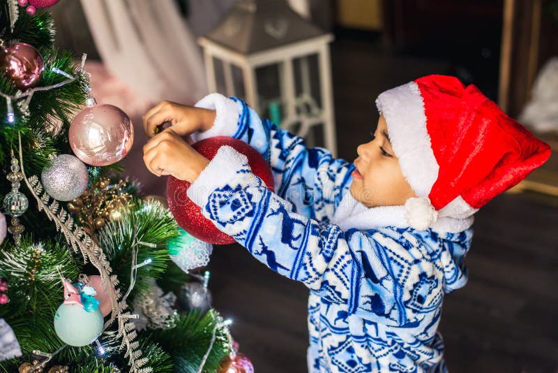 Afrikaans Amerikaans jongen gekleed kostuum Santa Claus die een Kerstboom verfraaien stock foto's Afrikaans Amerikaans jongen gekleed kostuum Santa Claus die een Kerstboom verfraaien stock foto's