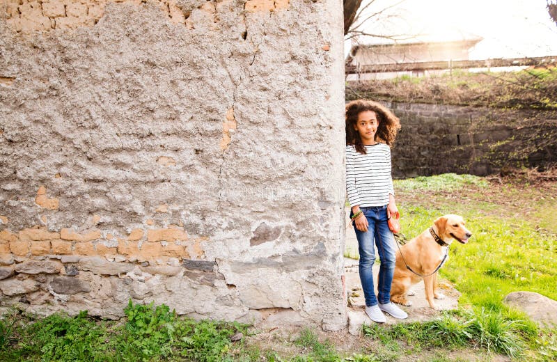 Afrikaans Amerikaans meisje met haar hond bij de concrete muur royalty-vrije stock foto Afrikaans Amerikaans meisje met haar hond bij de concrete muur royalty-vrije stock foto