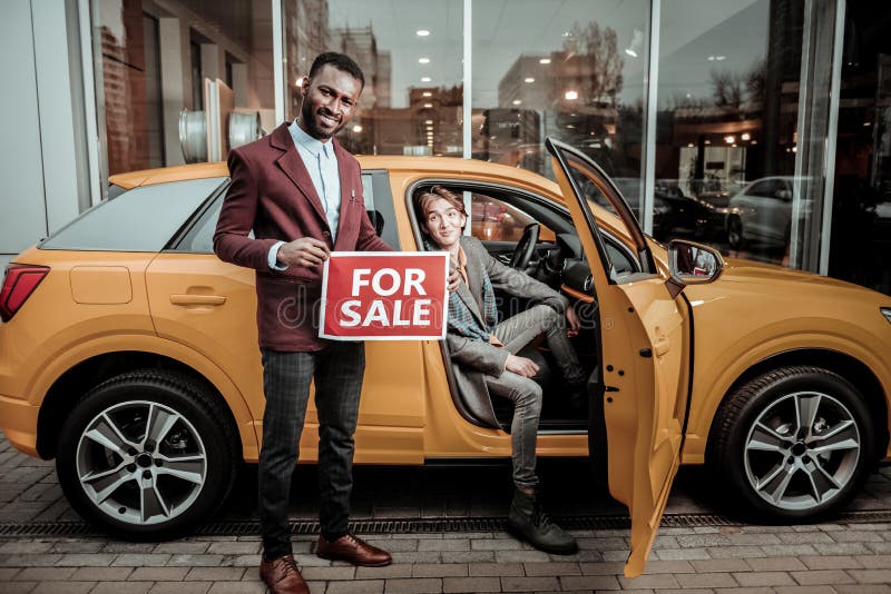 Afrikaans-Amerikaanse afdelingschef die aardige passagiers oranje auto verkopen stock afbeeldingen Afrikaans-Amerikaanse afdelingschef die aardige passagiers oranje auto verkopen stock afbeeldingen
