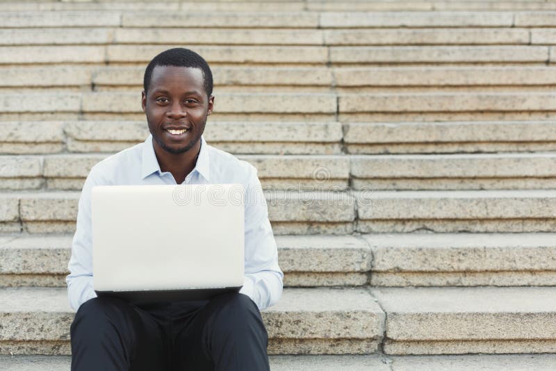 Afrikaans-Amerikaanse gelukkige zakenman die met laptop in openlucht werken stock afbeeldingen Afrikaans-Amerikaanse gelukkige zakenman die met laptop in openlucht werken stock afbeeldingen