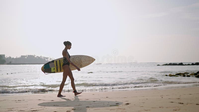 Afrikaans - amerikaanse vrouw die met een surfplank op het strand op de oceaan rondloopt. zwarte vrouwelijke surfer met surfplank.