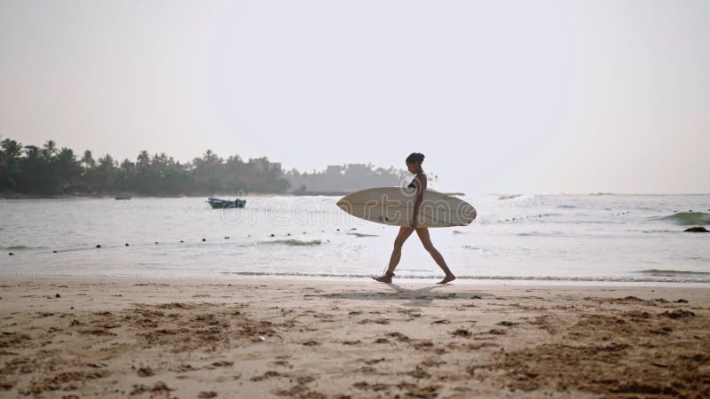 Afrikaans - amerikaanse vrouw die met een surfplank op het strand op de oceaan rondloopt. zwarte vrouwelijke surfer met surfplank.