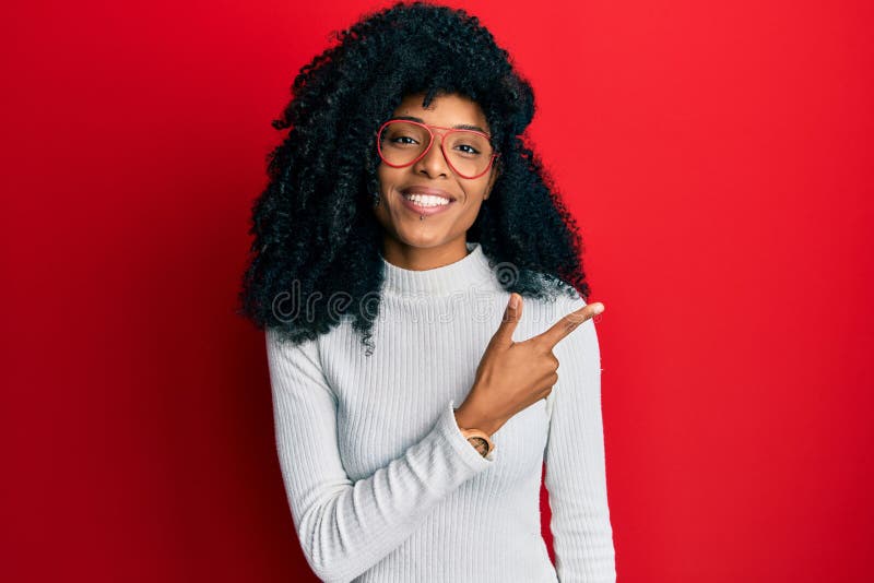 African american woman with afro hair wearing casual sweater and glasses smiling cheerful pointing with hand and finger up to the side. African american woman with afro hair wearing casual sweater and glasses smiling cheerful pointing with hand and finger up to the side