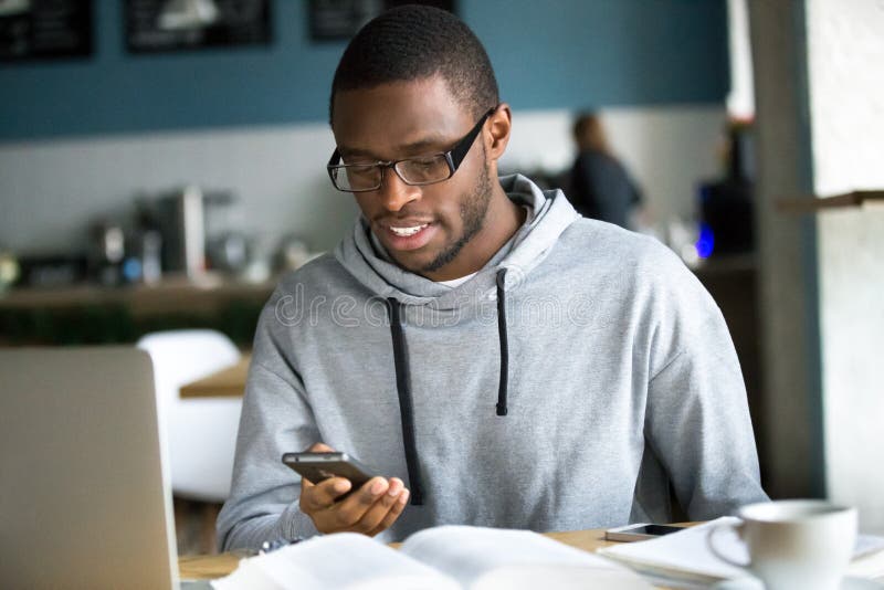 Afrikaanse Amerikaanse kerelzitting in koffie die gadgets gebruiken royalty-vrije stock fotografie Afrikaanse Amerikaanse kerelzitting in koffie die gadgets gebruiken royalty-vrije stock fotografie
