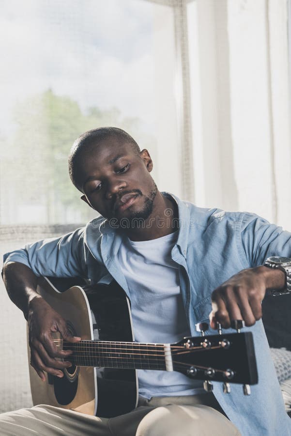 Afrikaanse Amerikaanse mens die akoestische gitaar stemmen stock afbeeldingen Afrikaanse Amerikaanse mens die akoestische gitaar stemmen stock afbeeldingen