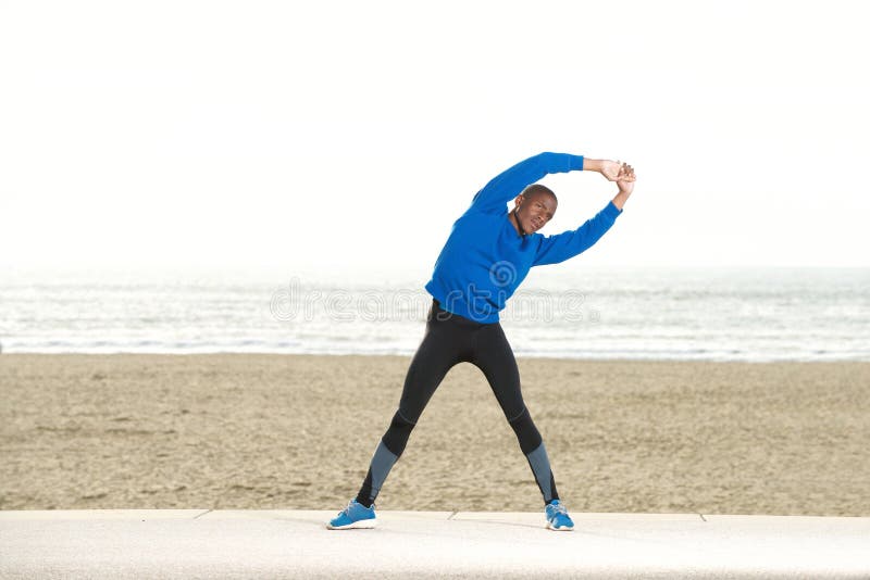 Full body portrait of african american man stretching muscles at the beach. Full body portrait of african american man stretching muscles at the beach