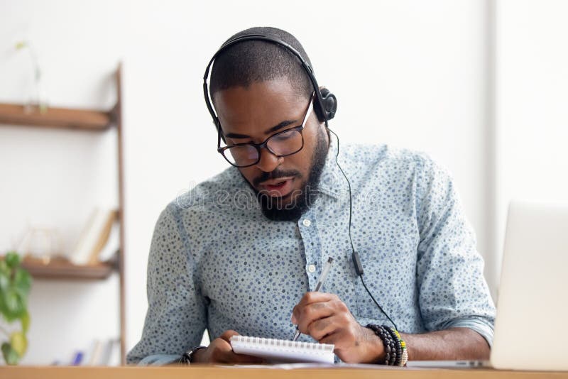 Afrikaanse Amerikaanse mens in hoofdtelefoons die e-Lerende cursus nemen op kantoor stock afbeelding Afrikaanse Amerikaanse mens in hoofdtelefoons die e-Lerende cursus nemen op kantoor stock afbeelding