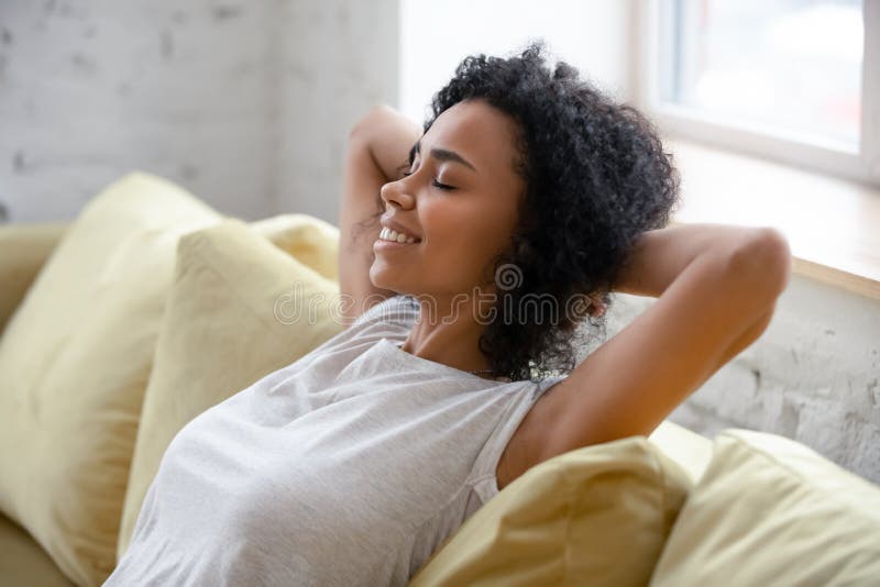 Afrikaanse Amerikaanse vrouw ontspannen zich thuis op een comfortabele bank