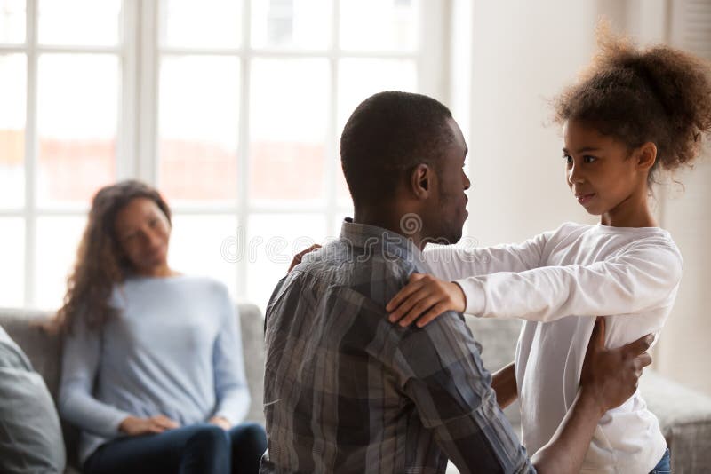 African dad talking to daughter supporting or explaining little mixed race girl during friendly conversation at home, black father speaking to child having good trustful relationships with kid. African dad talking to daughter supporting or explaining little mixed race girl during friendly conversation at home, black father speaking to child having good trustful relationships with kid