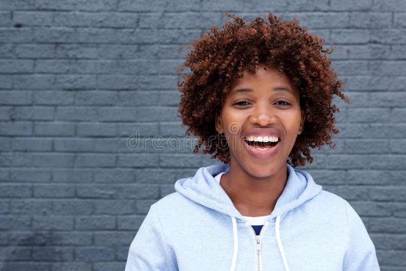 Afrikaanse vrouw die tegen grijze bakstenen muur lachen stock fotografie Afrikaanse vrouw die tegen grijze bakstenen muur lachen stock fotografie