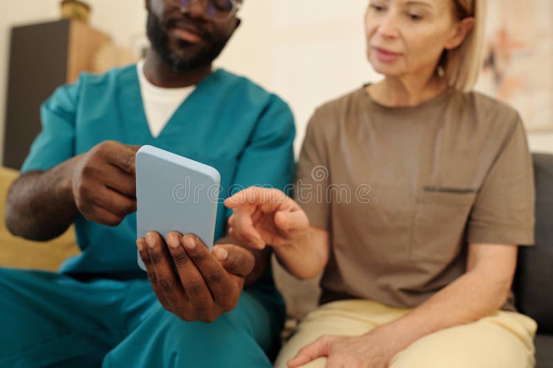 Afrikanische amerikanische Gesundheitsfachleute zeigen Gerät für ältere Frauen stockfotografie