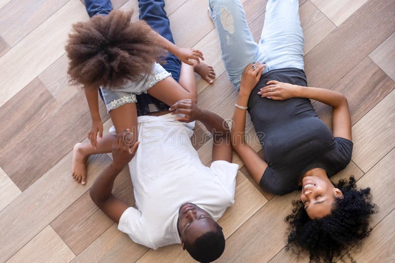 Afrikanische Familie der oben genannten Ansicht, die zu Hause auf warmem Boden liegt lizenzfreie stockfotografie Afrikanische Familie der oben genannten Ansicht, die zu Hause auf warmem Boden liegt lizenzfreie stockfotografie