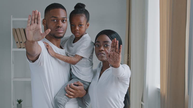 Afrikanische familie schwarz ernst jung afro eltern mit kleine tochter stehen drinnen halten ihre palmen vor