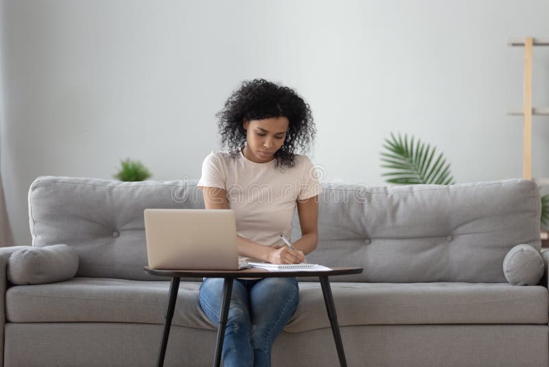Afrikanische Frau, die am Kaffeetisch sitzt und Stift zum Schreiben hält lizenzfreies stockfoto