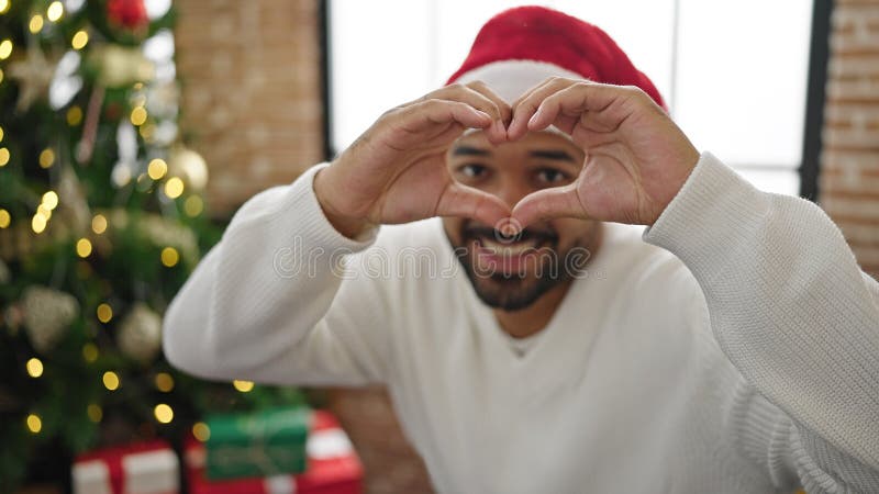 Afrikanischer Amerikaner feiert Weihnachten und macht dabei mit Händen zu Hause Herzform lizenzfreie stockfotografie