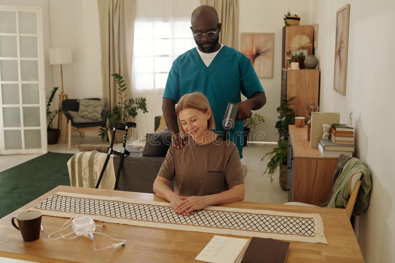 Afrikanischer amerikanischer Betreuer Unterstützung Senior Woman bei Massage lizenzfreies stockfoto