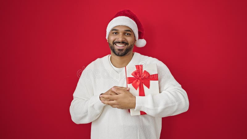 Afrikanischer amerikanischer Mann mit Weihnachtsgeschenk über isolierten roten Hintergrund stockbild