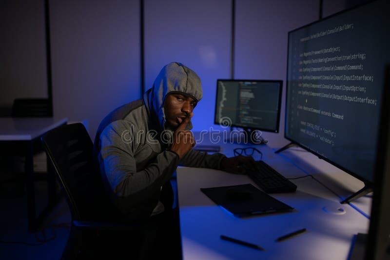Afrikanischer Hacker-Programmierer, der Computer im Dunklen Raum verwendet stockbilder