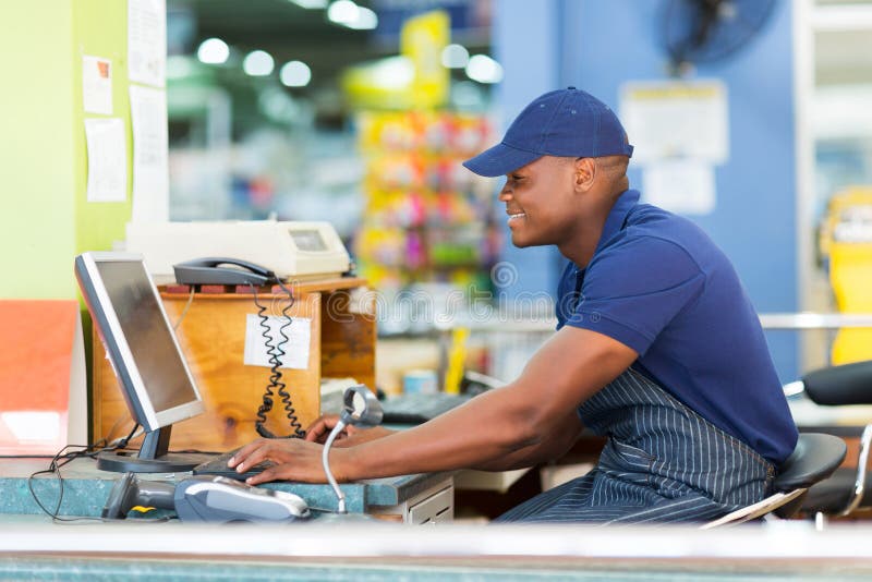 Happy african male cashier working at till point in supermarket. Happy african male cashier working at till point in supermarket