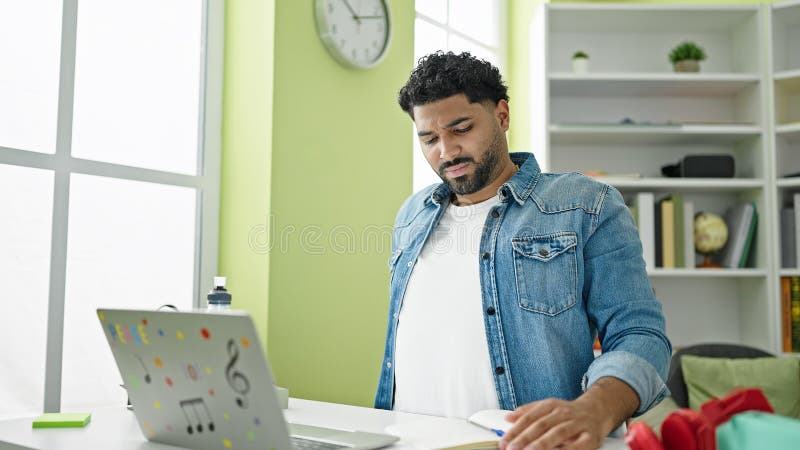 Afrikanischer Student, der an der Universität der Bibliothek Notizen mit Rückenschmerzen schreibt