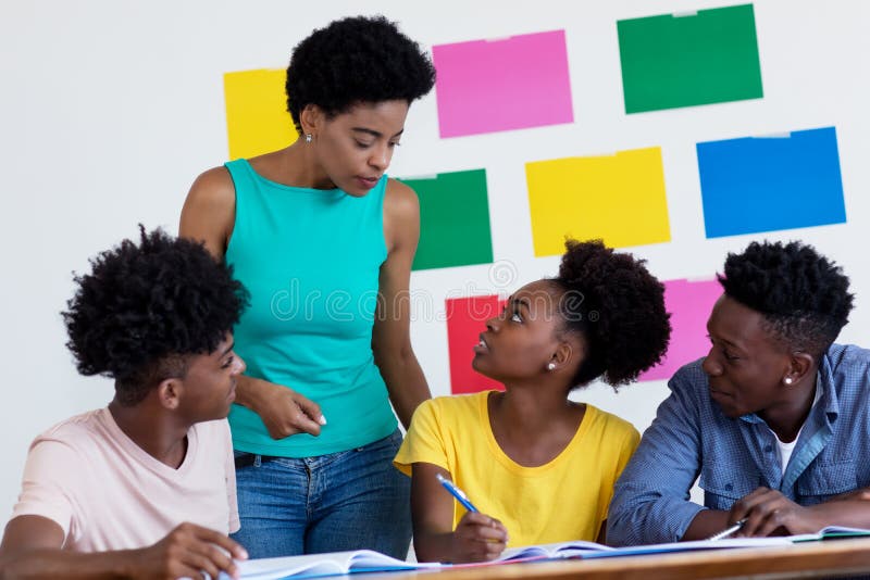 African american female teacher talking with students at classroom of school. African american female teacher talking with students at classroom of school