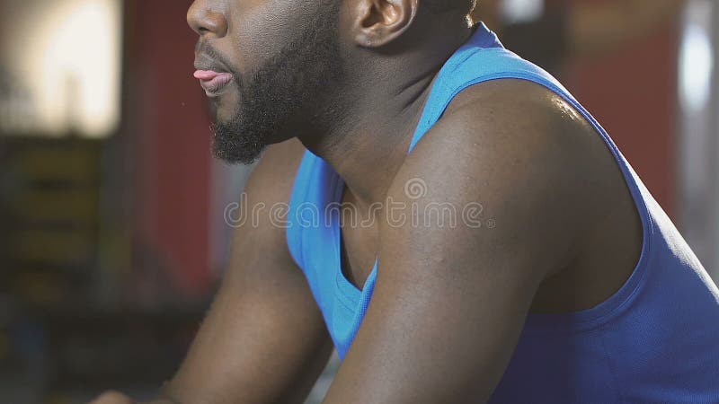 Afrikansk amerikan som torkar hans framsida med handduken i idrottshallen som evakueras, når utbildning