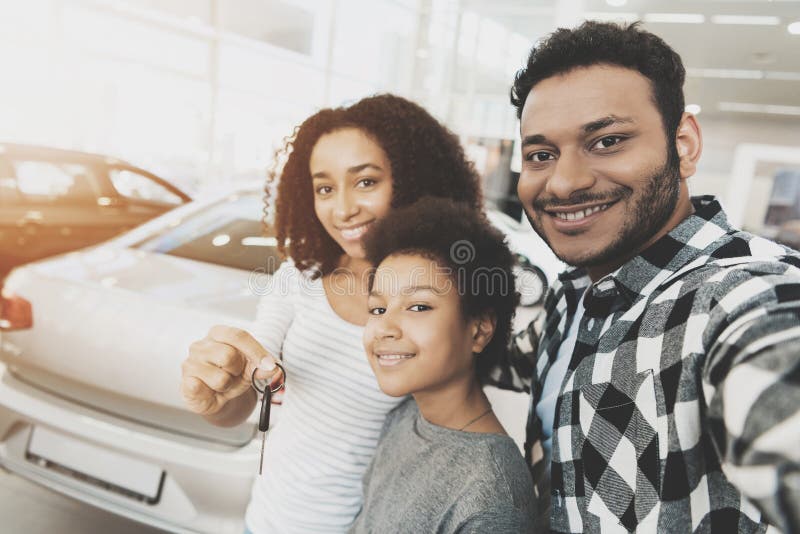 Afrikansk amerikanfamilj på bilåterförsäljaren Modern, fadern och sonen tar selfie med tangenter för ny bil arkivbild Afrikansk amerikanfamilj på bilåterförsäljaren Modern, fadern och sonen tar selfie med tangenter för ny bil arkivbild