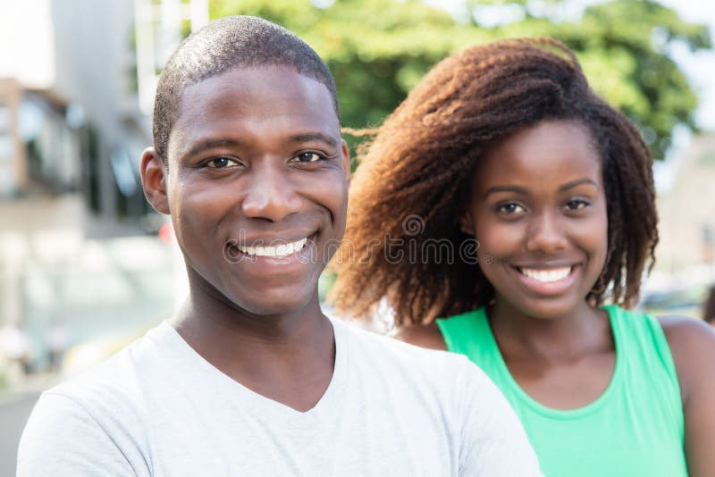 Afrikansk amerikanförälskelsepar som ser kameran i staden arkivbild Afrikansk amerikanförälskelsepar som ser kameran i staden arkivbild