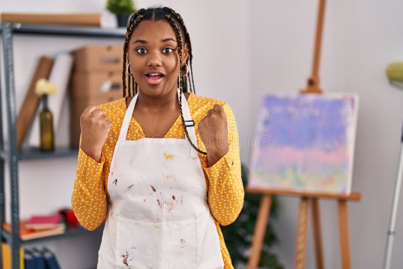 Afrikansk amerikansk kvinna med braider vid konststudion som skriker stolt över seger och framgångar väldigt upphetsade med upphöj arkivbilder