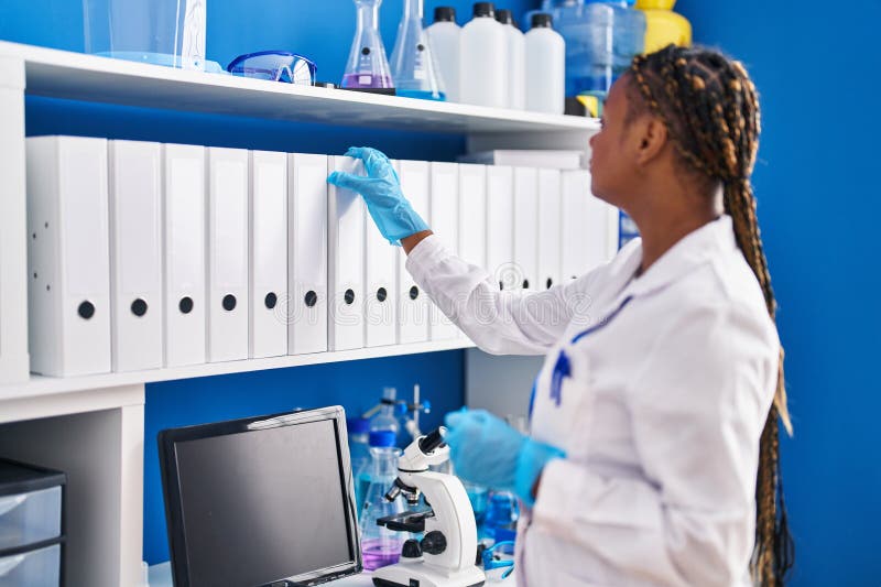 Afrikansk amerikansk kvinnlig forskare som håller binder på laboratoriet arkivfoto