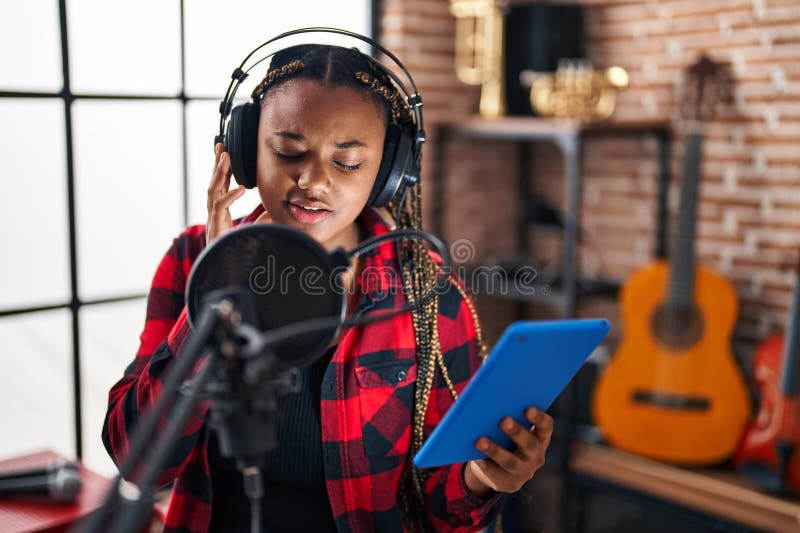 Afrikansk amerikansk musiker sjunger med touchpad på musikstudio royaltyfria bilder