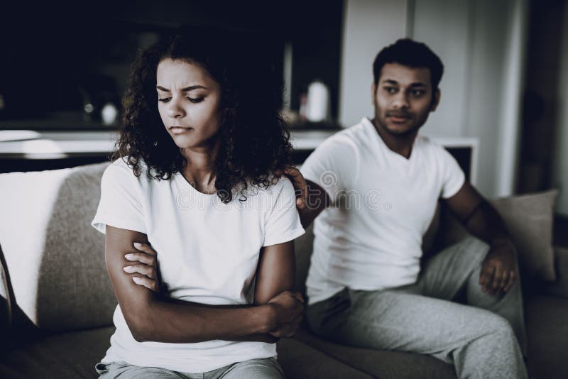 Afro American Couple On Couch. Quarrel Concept. Family Misunderstanding. Disappointed Sweatheart`s Disharmony. Unhappy Female Deny. Couple Unhappy Holiday. Arms Akimbo. Begging For Apologize.