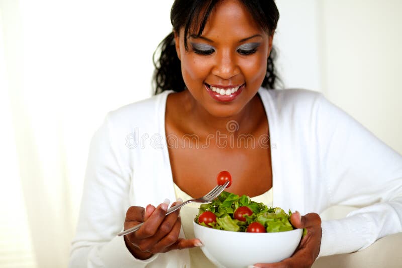 Portrait of an afro-American young woman eating fresh vegetable salad at soft colors composition. Portrait of an afro-American young woman eating fresh vegetable salad at soft colors composition