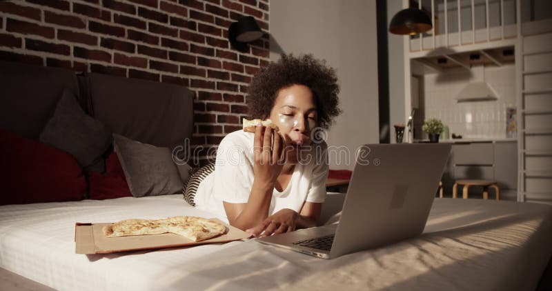 Afro-américaine mangeant de la pizza en regardant un film banque de vidéos