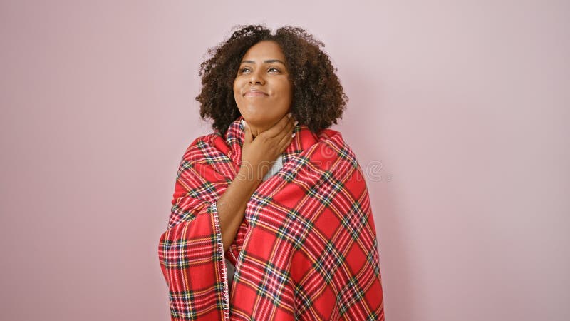 Afro-américaine souriante dans un châle rouge plaid sur fond rose images stock
