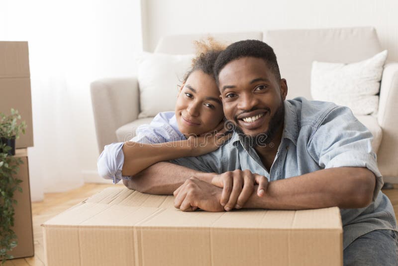 Afro Spouses Embracing Among Unpacked Moving Boxes In New Flat stock photography Afro Spouses Embracing Among Unpacked Moving Boxes In New Flat stock photography