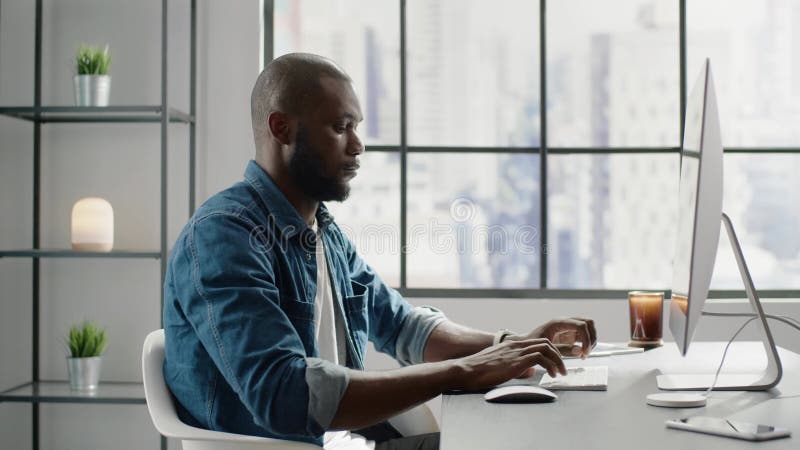 Afroamerican financial analyst types report on computer clips vidéos