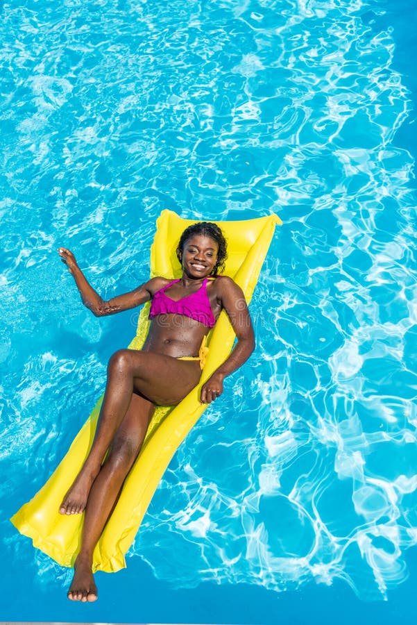 Afroamerikanerfrau, die auf aufblasbare Matratze schwimmt lizenzfreies stockbild Afroamerikanerfrau, die auf aufblasbare Matratze schwimmt lizenzfreies stockbild