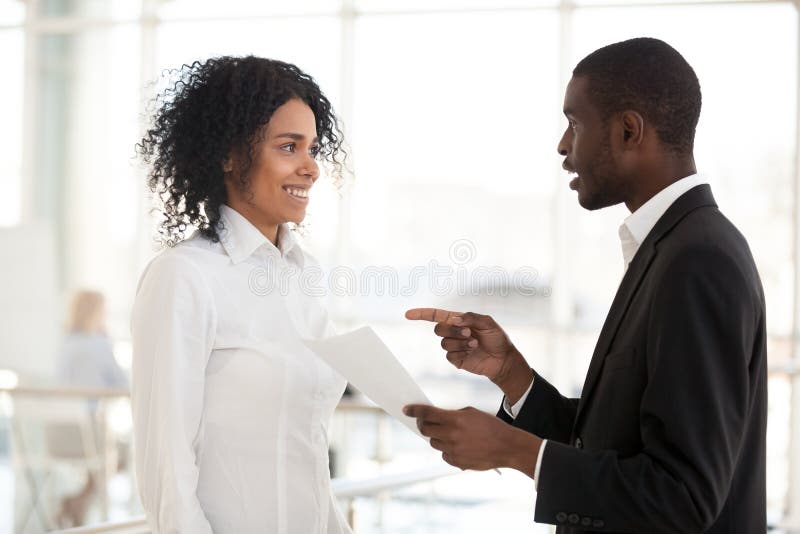 African American businessman talk to excited female black employee, telling good news about promotion or achievement, boss praise intern, diverse millennial workers chat in hallway. Reward concept. African American businessman talk to excited female black employee, telling good news about promotion or achievement, boss praise intern, diverse millennial workers chat in hallway. Reward concept