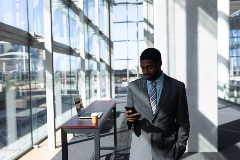 Afroamerikanisch vom Geschäftsmann, der Handy im Büro verwendet stockfoto Afroamerikanisch vom Geschäftsmann, der Handy im Büro verwendet stockfoto