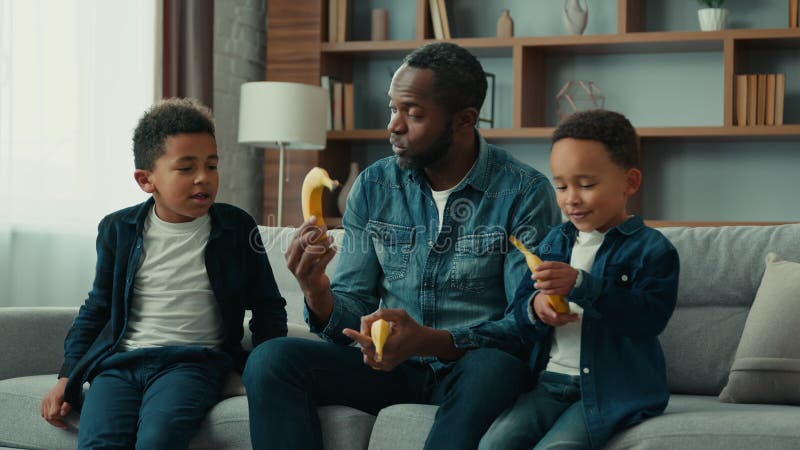 Afrykańska amerykańska rodzina w domu samotny ojciec mężczyzna z dwójką dzieci chłopcy tata rozmawiający z dziećmi dają owoce z ba