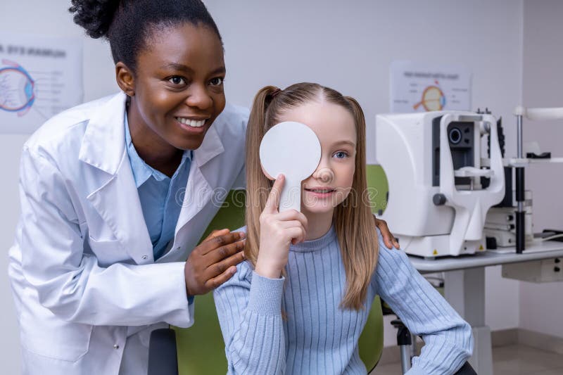 Afrykański american optometrist pracujący z małym pacjentem i wyglądający przyjaznie zdjęcie stock