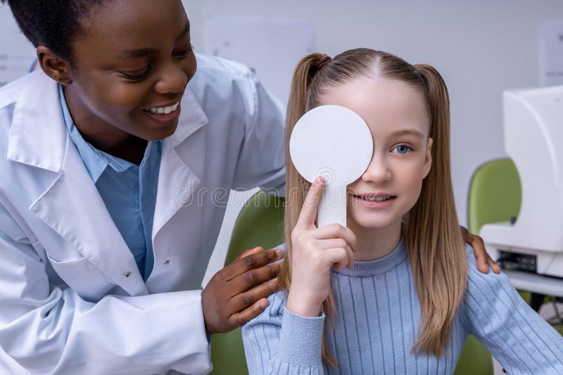 Afrykański american optometrist pracujący z małym pacjentem i wyglądający przyjaznie obrazy stock