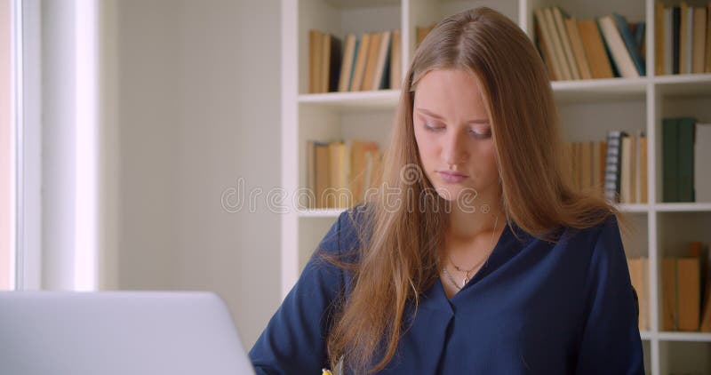 Afsluiten van het portret van jonge succesvolle kaukasische zakenvrouw die notities aanneemt binnen in het kantoor